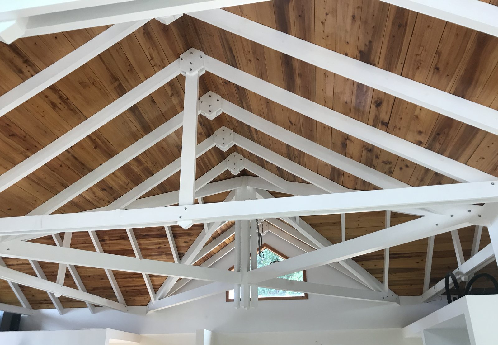 White painted trusses and ceiling boards seen from below