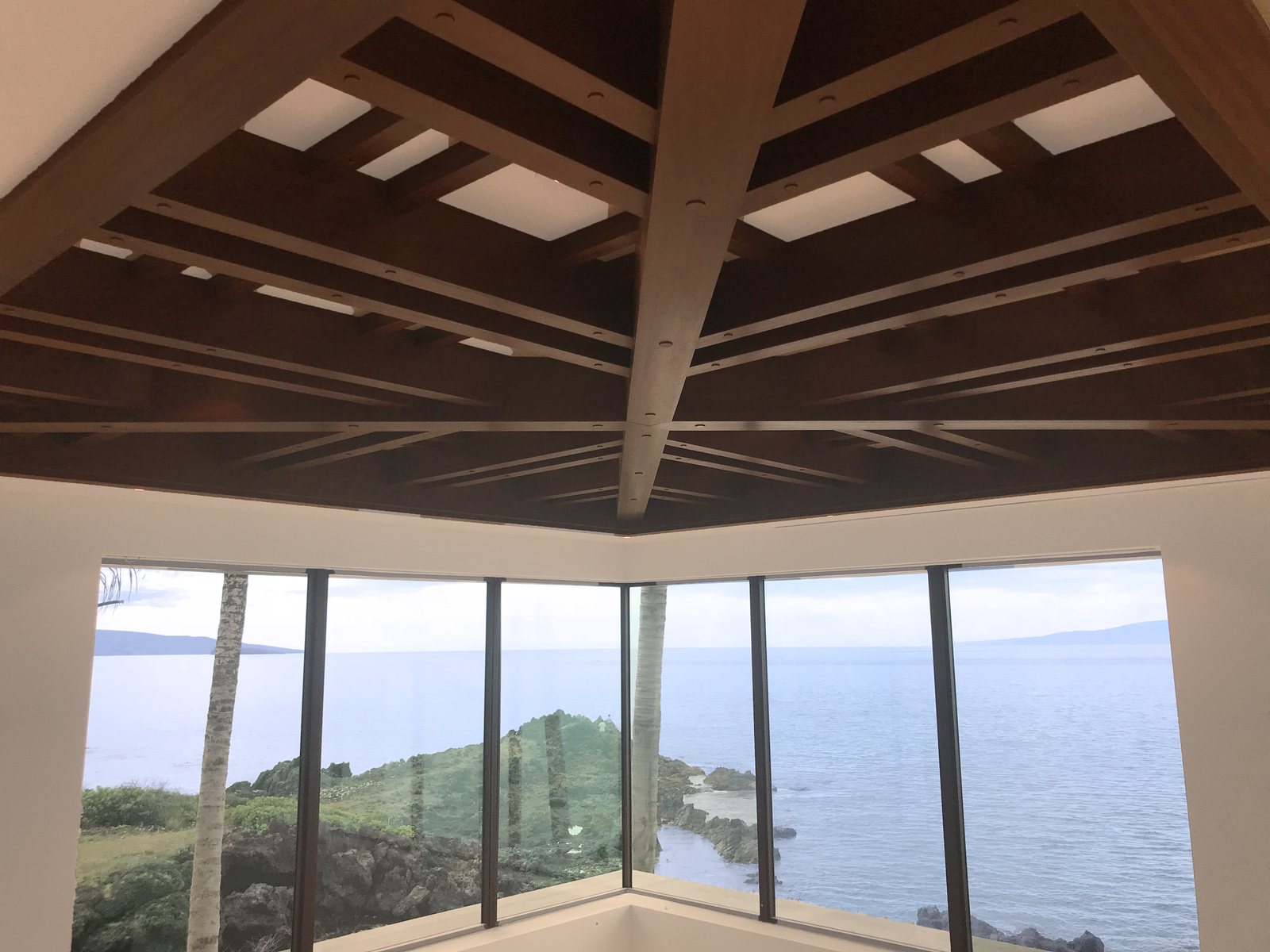 Box beams running up a pitched ceiling toward a glazed wall