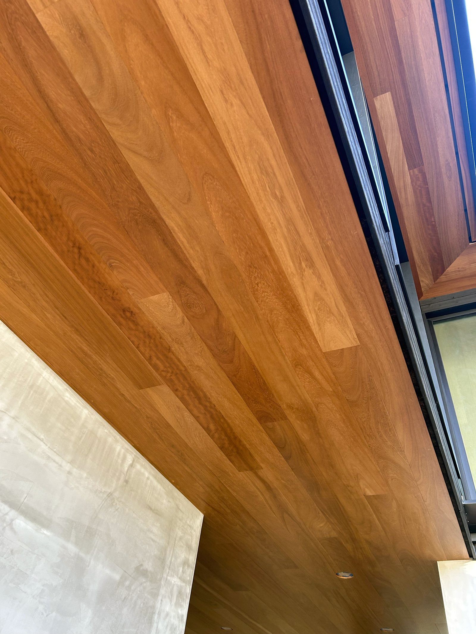 Hardwood cladding running past a window head where the plane changes